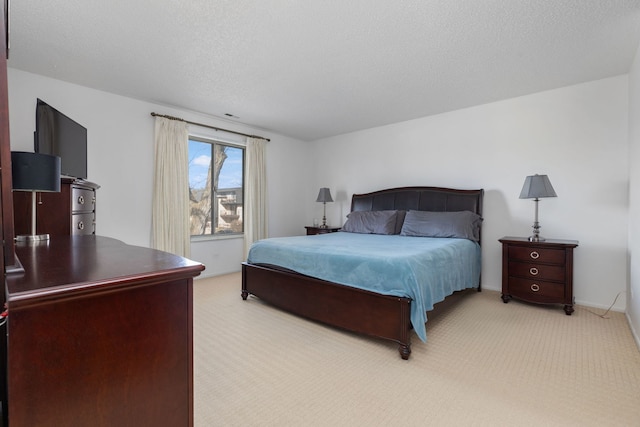 bedroom with light colored carpet, baseboards, and a textured ceiling