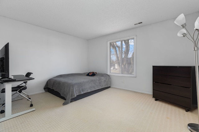 carpeted bedroom featuring baseboards, visible vents, and a textured ceiling