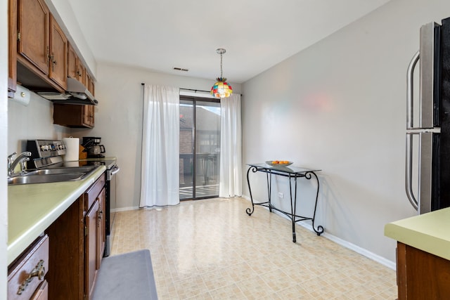 kitchen with baseboards, visible vents, light countertops, pendant lighting, and fridge