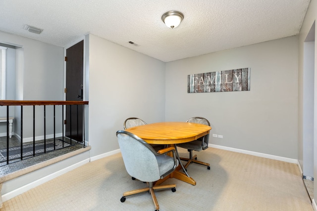 dining space with visible vents, a textured ceiling, baseboards, and carpet