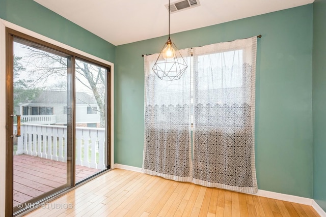 unfurnished dining area with wood finished floors, visible vents, and baseboards