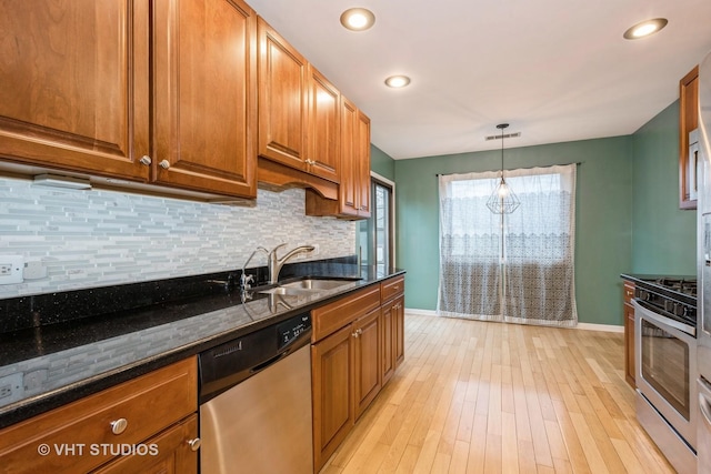 kitchen with brown cabinetry, backsplash, stainless steel appliances, and a sink