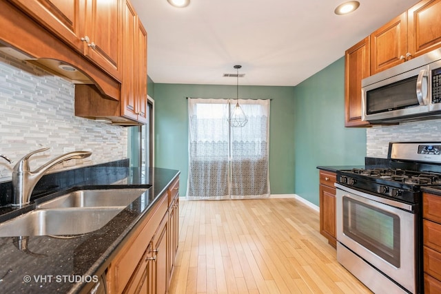 kitchen with visible vents, a sink, appliances with stainless steel finishes, light wood finished floors, and baseboards