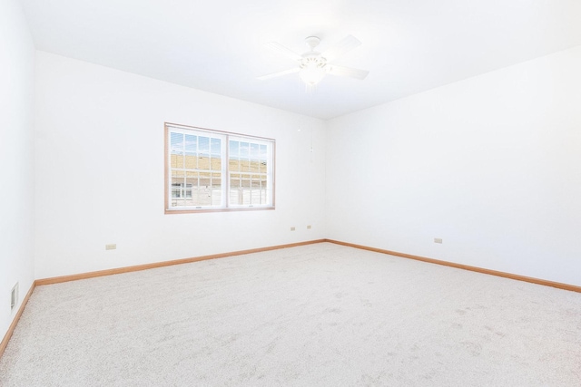 carpeted spare room with visible vents, baseboards, and a ceiling fan