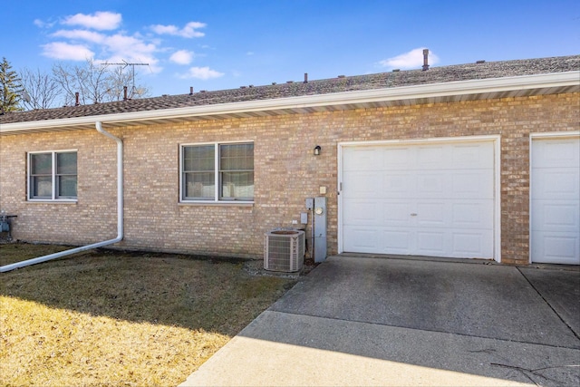 exterior space with cooling unit, brick siding, an attached garage, and driveway