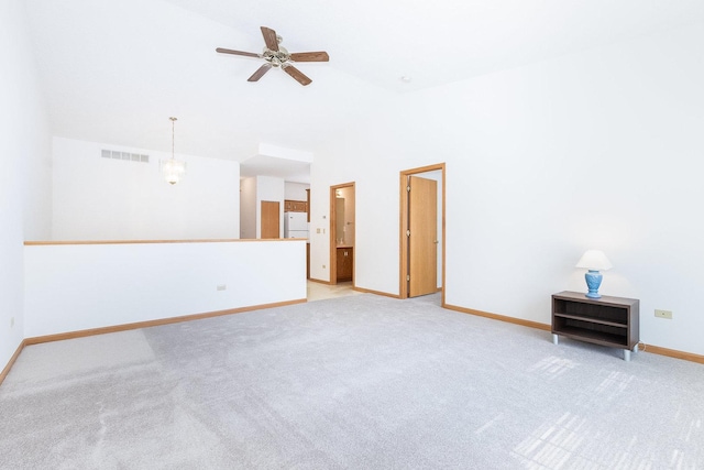 interior space with visible vents, baseboards, light carpet, ceiling fan with notable chandelier, and a high ceiling