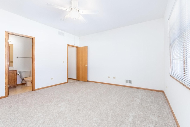 unfurnished bedroom featuring light colored carpet, visible vents, ensuite bathroom, and baseboards