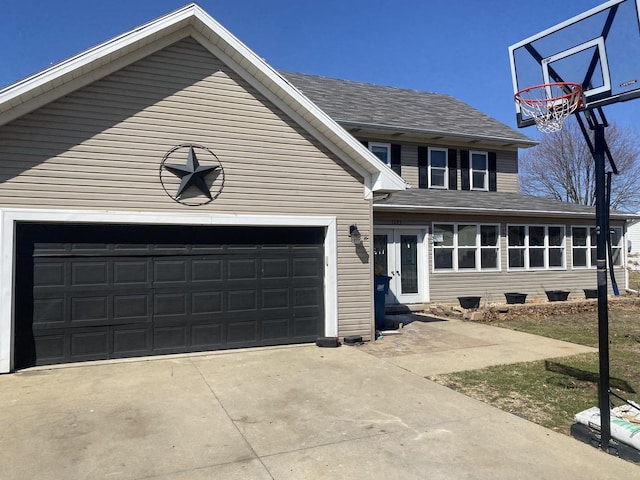 traditional home featuring driveway, an attached garage, and a shingled roof