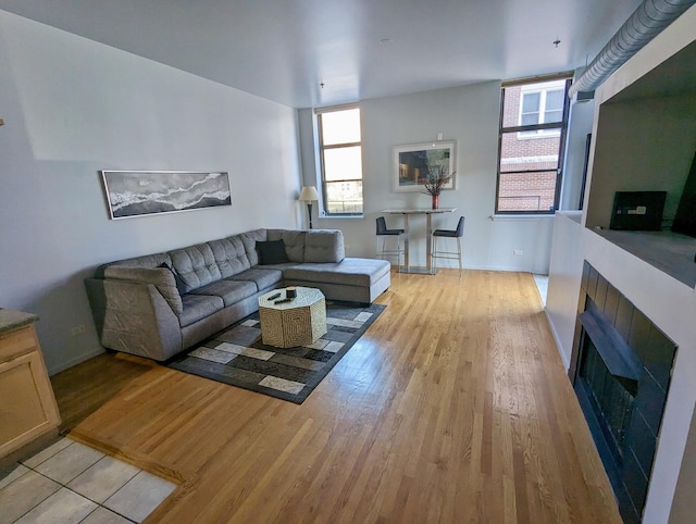 living area with baseboards, light wood-style floors, and a fireplace