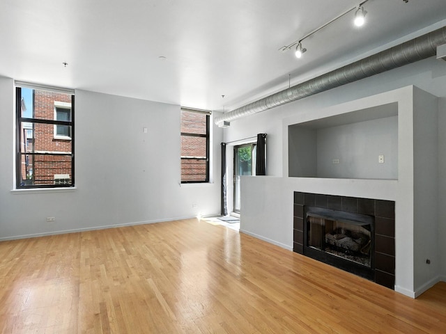 1000 E 53rd St Unit 112, Chicago, IL 60615 - unfurnished living room with wood finished floors, a tiled fireplace, plenty of natural light, and rail lighting