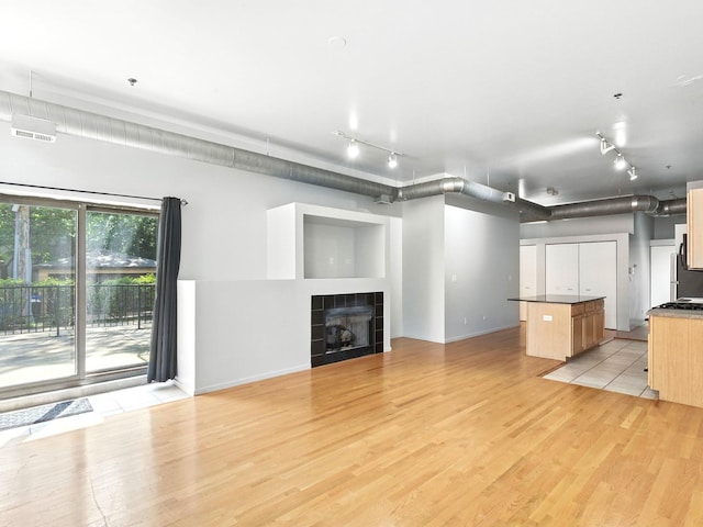 1000 E 53rd St Unit 112, Chicago, IL 60615 - unfurnished living room with track lighting, a tiled fireplace, and light wood-type flooring