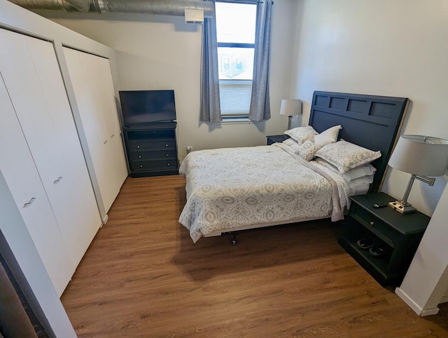 bedroom with multiple closets and wood finished floors