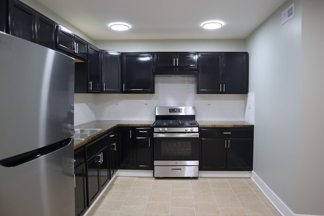 kitchen featuring dark cabinetry, visible vents, a sink, stainless steel appliances, and tasteful backsplash