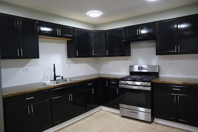 kitchen with dark cabinetry, a sink, stainless steel gas stove, tasteful backsplash, and butcher block counters