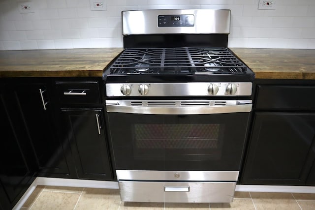 kitchen featuring dark cabinetry, tasteful backsplash, stainless steel gas stove, and butcher block counters