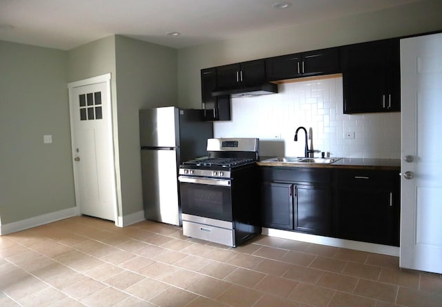 kitchen with baseboards, a sink, stainless steel appliances, tasteful backsplash, and dark cabinets