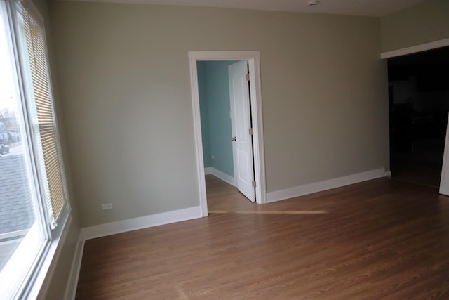 empty room with a wealth of natural light, baseboards, and wood finished floors