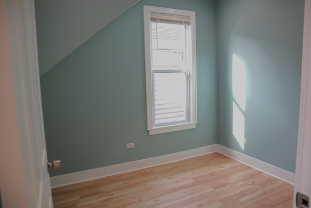 additional living space with vaulted ceiling, light wood finished floors, baseboards, and a wealth of natural light