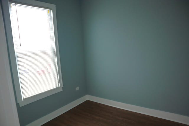 unfurnished room featuring baseboards and dark wood-style flooring