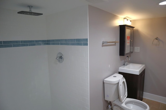 bathroom with baseboards, toilet, vanity, and a tile shower