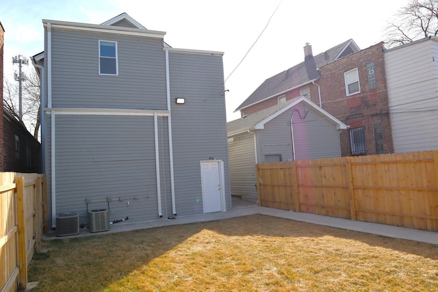 rear view of property featuring a yard, cooling unit, and a fenced backyard