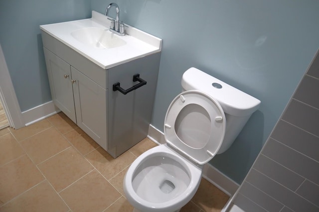 half bath with vanity, tile patterned floors, toilet, and baseboards