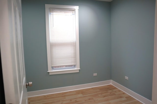 spare room featuring baseboards and light wood-style floors