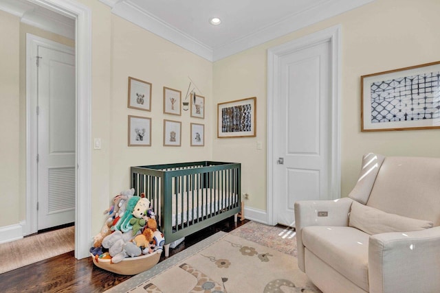 bedroom with crown molding, visible vents, baseboards, a crib, and wood finished floors