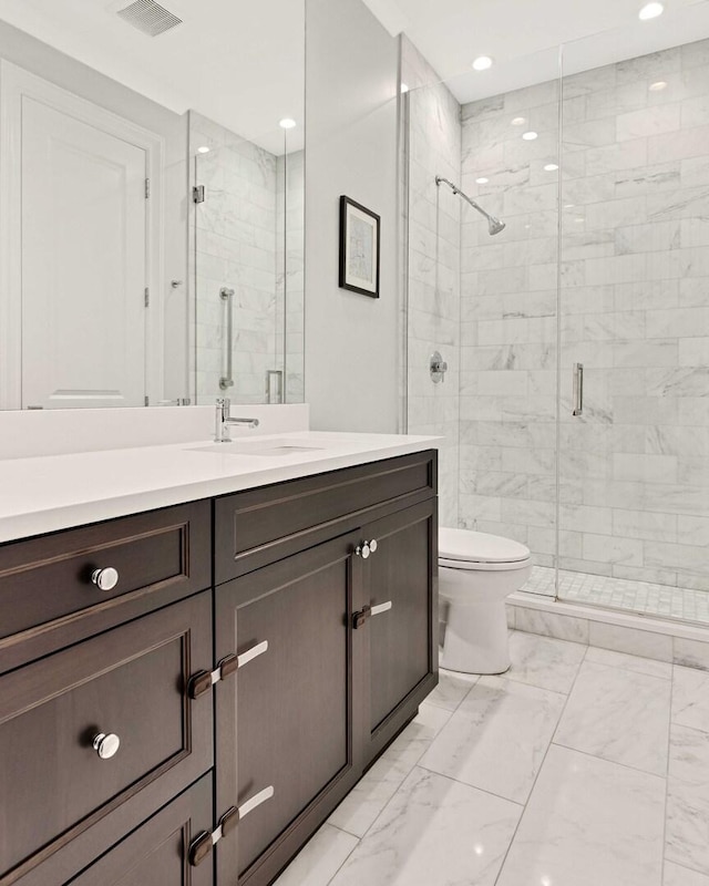 bathroom featuring vanity, toilet, a stall shower, marble finish floor, and visible vents