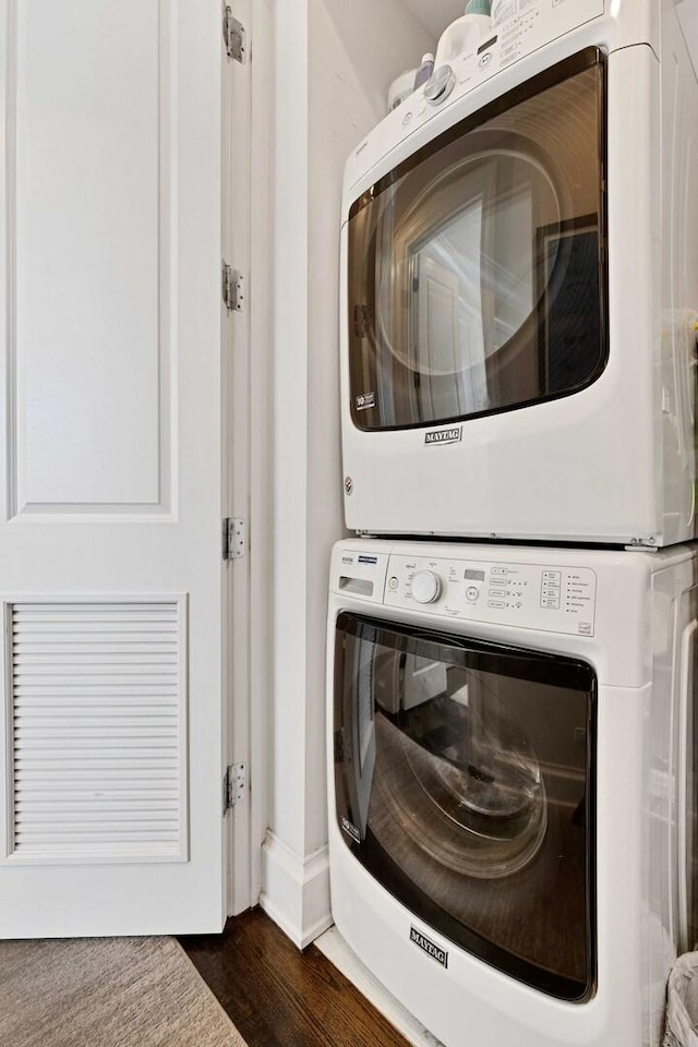 laundry area with stacked washing maching and dryer, dark wood-style floors, and laundry area