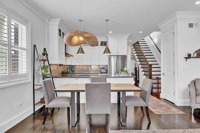 dining area featuring dark wood finished floors, visible vents, baseboards, and a healthy amount of sunlight