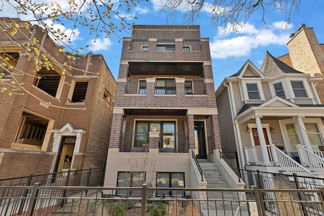 view of property featuring fence, stairway, a balcony, and brick siding