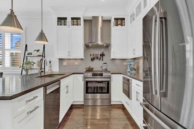 kitchen with crown molding, wall chimney exhaust hood, dark countertops, and appliances with stainless steel finishes