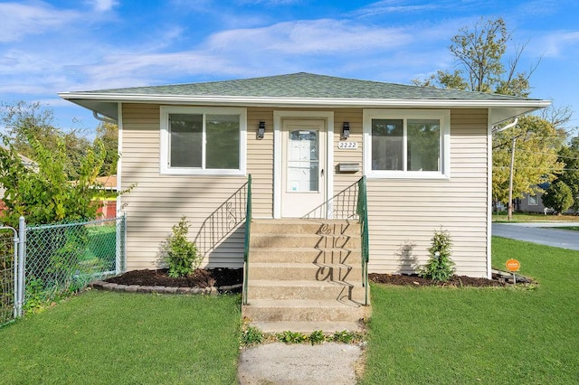 bungalow-style house featuring roof with shingles, a front lawn, and fence