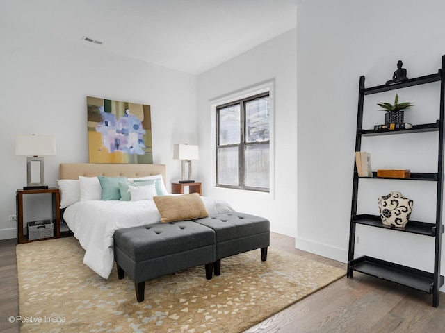 bedroom with visible vents, wood finished floors, and baseboards