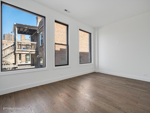 spare room featuring visible vents, baseboards, and wood finished floors