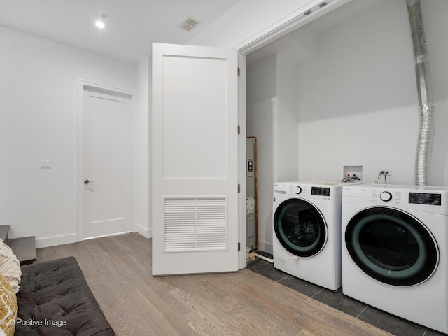 laundry area featuring visible vents, light wood-type flooring, water heater, laundry area, and separate washer and dryer