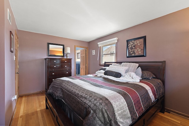 bedroom featuring visible vents, baseboards, and wood finished floors