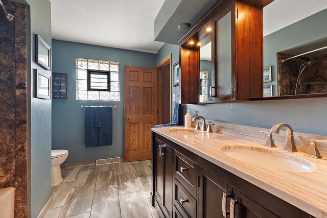 full bathroom featuring a sink, visible vents, toilet, and double vanity