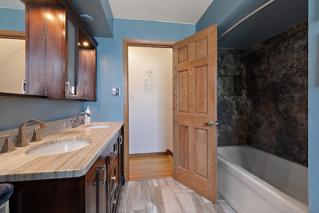 bathroom featuring a sink, baseboards, wood finished floors, and double vanity