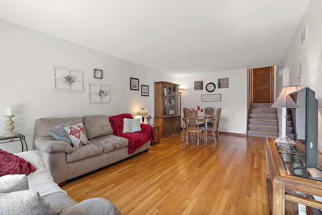 living area featuring stairway, visible vents, and light wood-type flooring