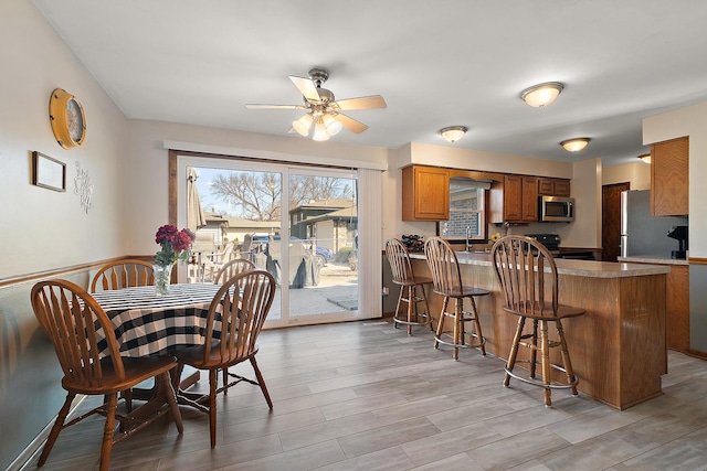 dining room featuring light wood-type flooring and a ceiling fan