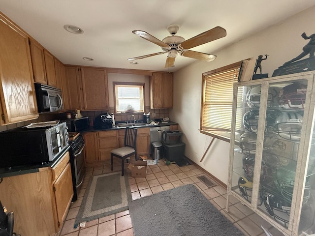 kitchen with appliances with stainless steel finishes, light tile patterned floors, ceiling fan, dark countertops, and recessed lighting