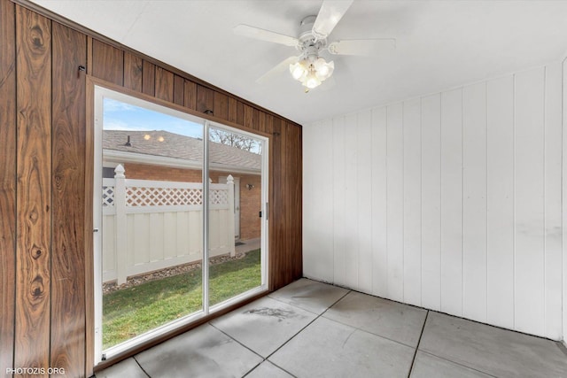 spare room with plenty of natural light, ceiling fan, and wooden walls