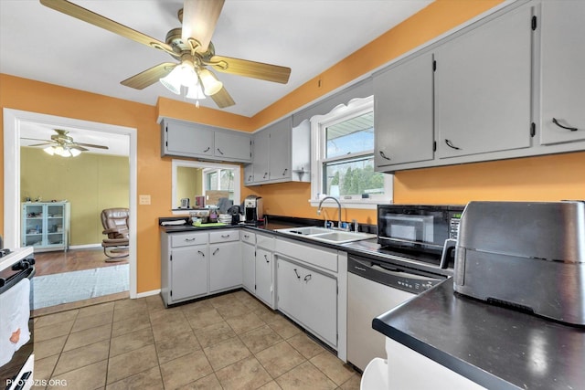 kitchen featuring dark countertops, black microwave, ceiling fan, stainless steel dishwasher, and a sink