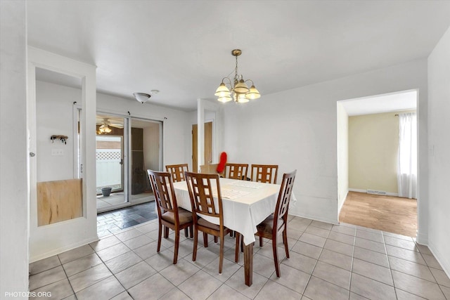 dining room with light tile patterned flooring, visible vents, baseboards, and an inviting chandelier