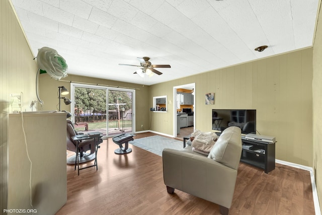 living area featuring a ceiling fan, wood finished floors, and baseboards