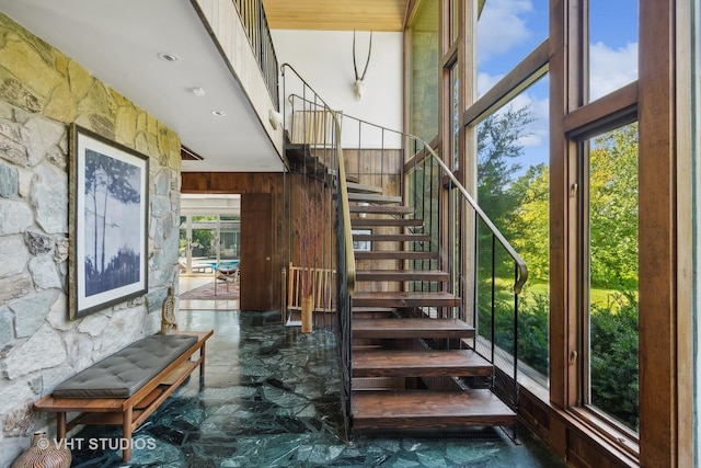 stairs featuring wood walls, marble finish floor, and a towering ceiling