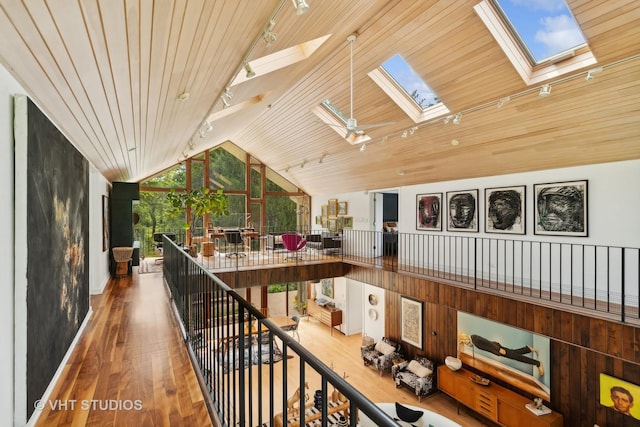 hallway featuring wood ceiling, rail lighting, wood finished floors, and vaulted ceiling with skylight