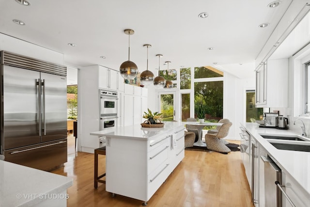kitchen with a sink, light countertops, a kitchen island, and stainless steel appliances